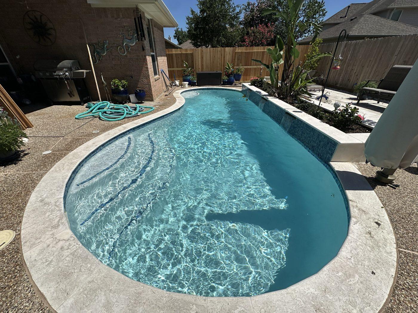 Freeform customer pool with a tanning ledge and raised spillover wall